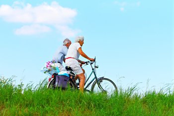 A happy elderly couple keep fit and healthy by riding bicycles while enjoying the great outdoors