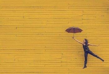 Happy and healthy woman floating with umbrella with colourful background behind living a good life